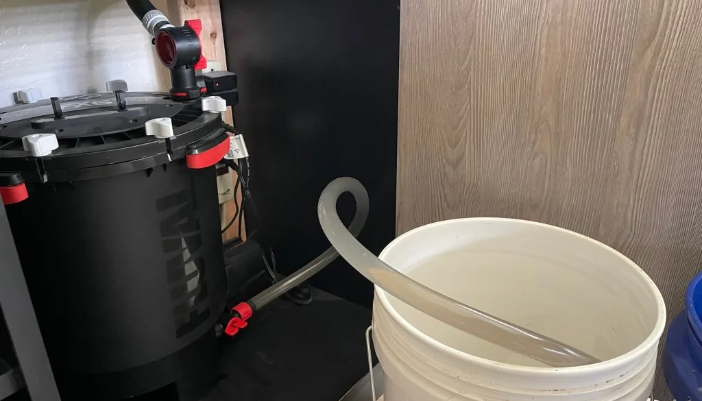 Filtro canister instalado dentro do móvel do aquário com mangueira de drenagem