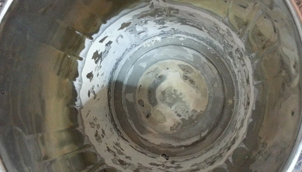 Crosta branca de calcário (carbonato de cálcio) deixada pela água dura no interior de uma panela de inox